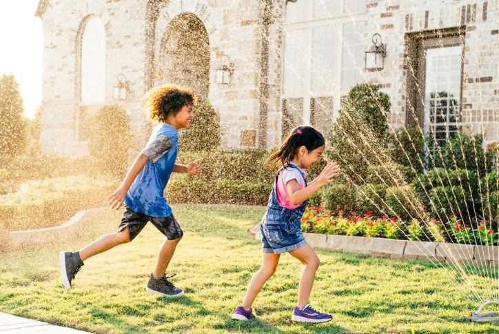 Kids playing in sprinkler.