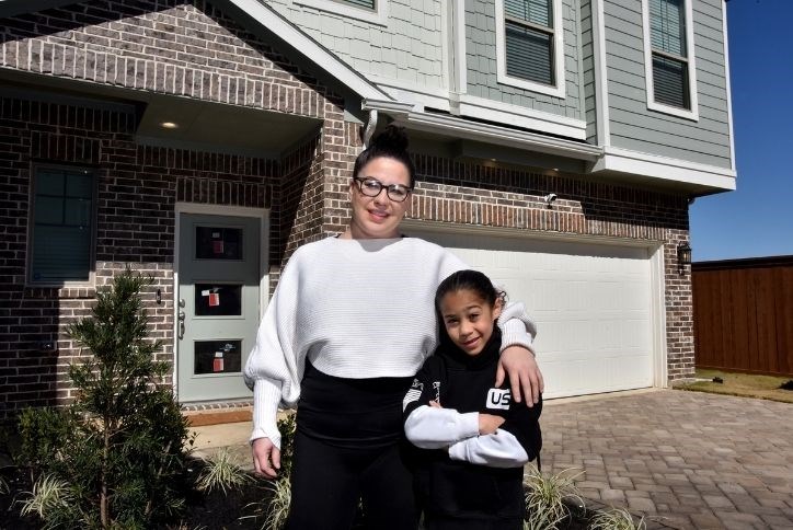 Torres Family posing in front of their new Chesmar Courtyard Collection home in Elyson in Katy, TX